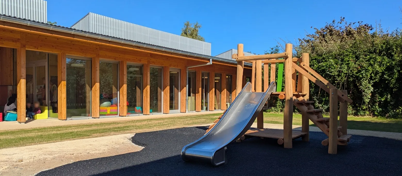 La façade en bois de la crèche Les Petits Moussaillons et le toboggan de son espace extérieur.